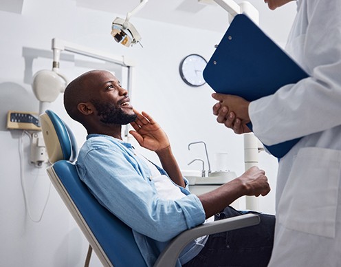 Smiling patient talking to dentist holding clipboard