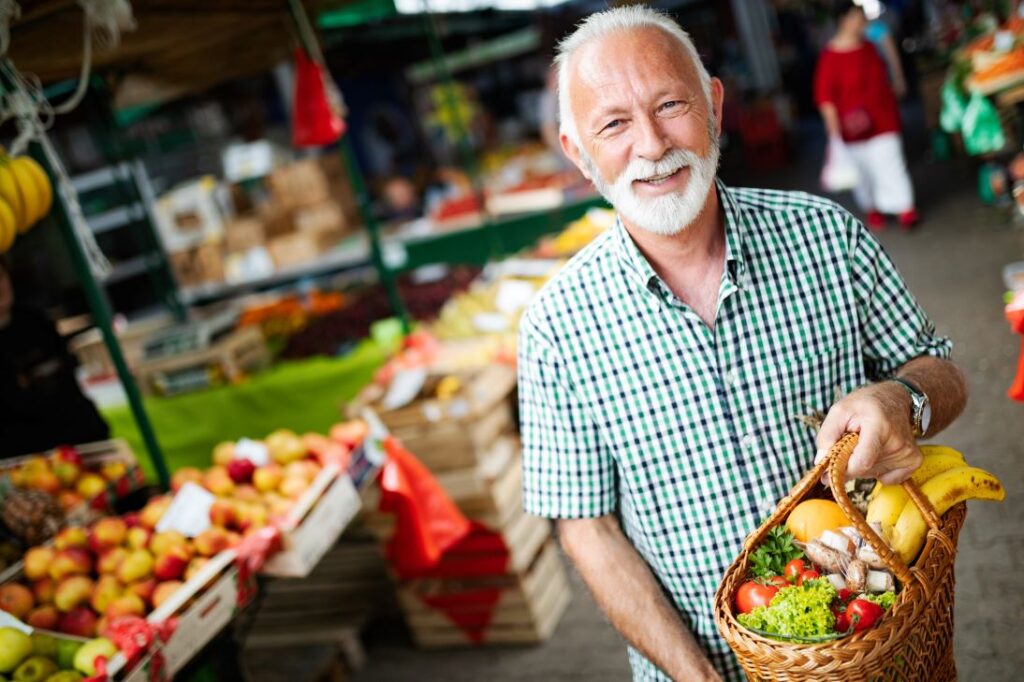 An older man buying fruit at a market.